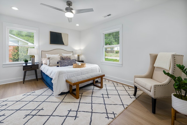 white bedroom with white and black rug and dark wood floors